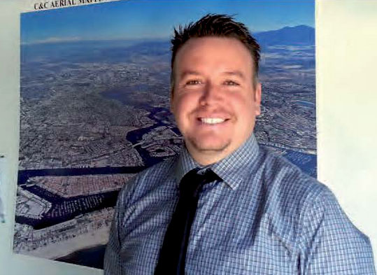 Robert Lafica, President of Central Coast Aerial Mapping, in front of a large-format aerial map